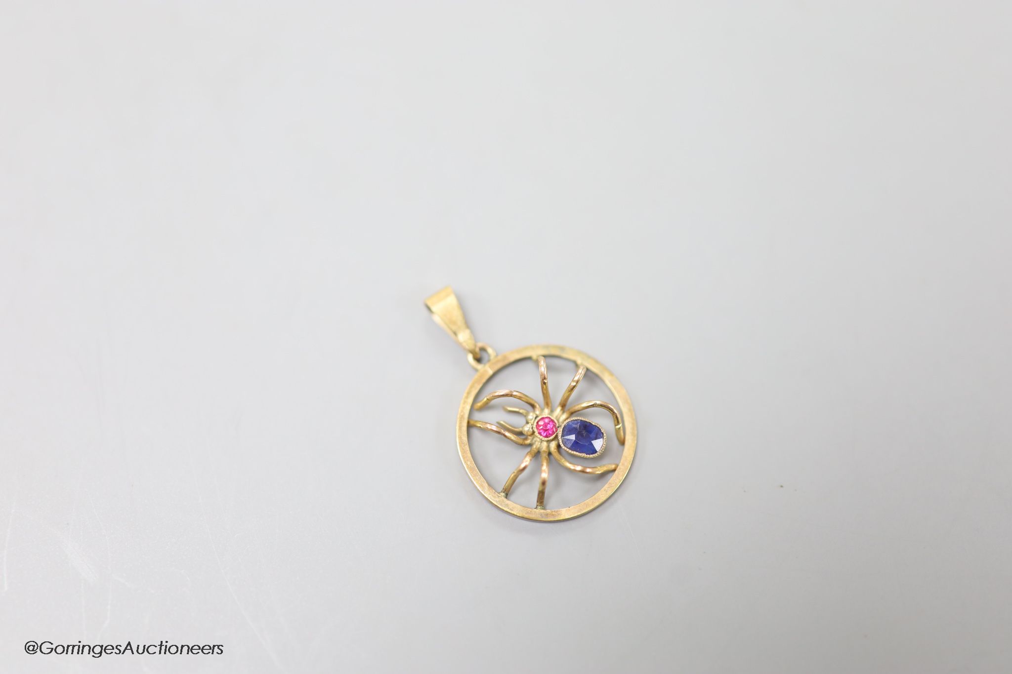 A 9ct, sapphire and ruby set circular spider pendant, 19mm, gross weight 1.9 grams.